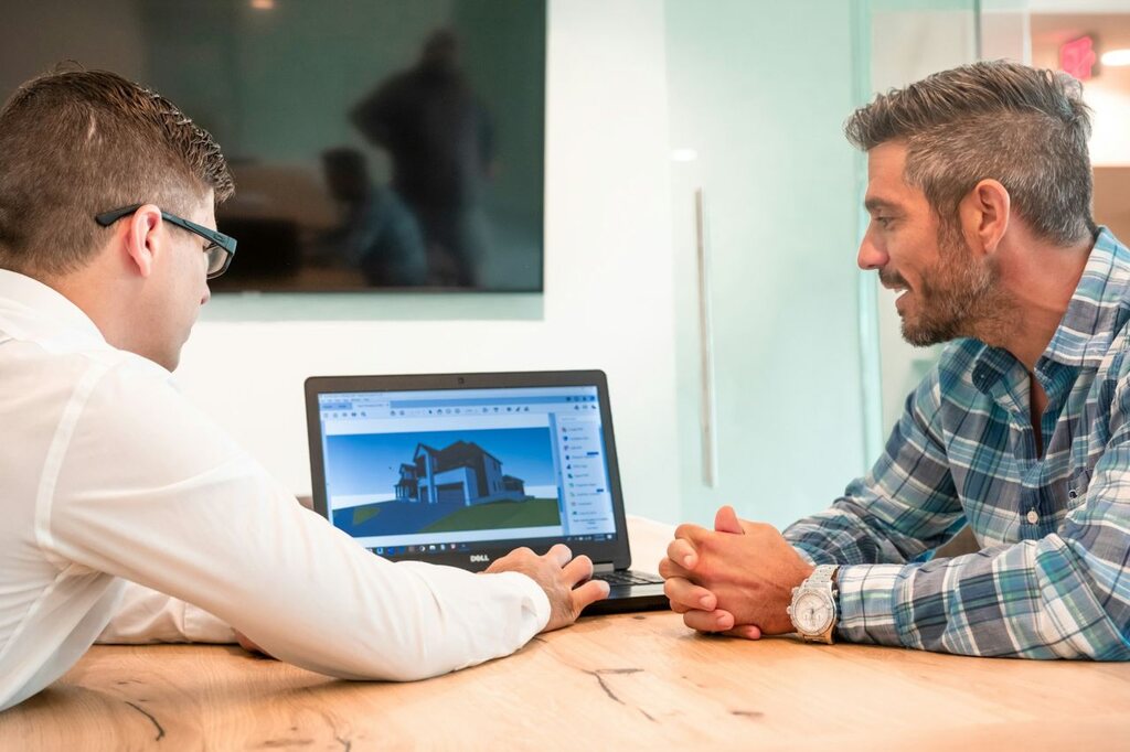 An engineer and a client sit together discussing home building plans