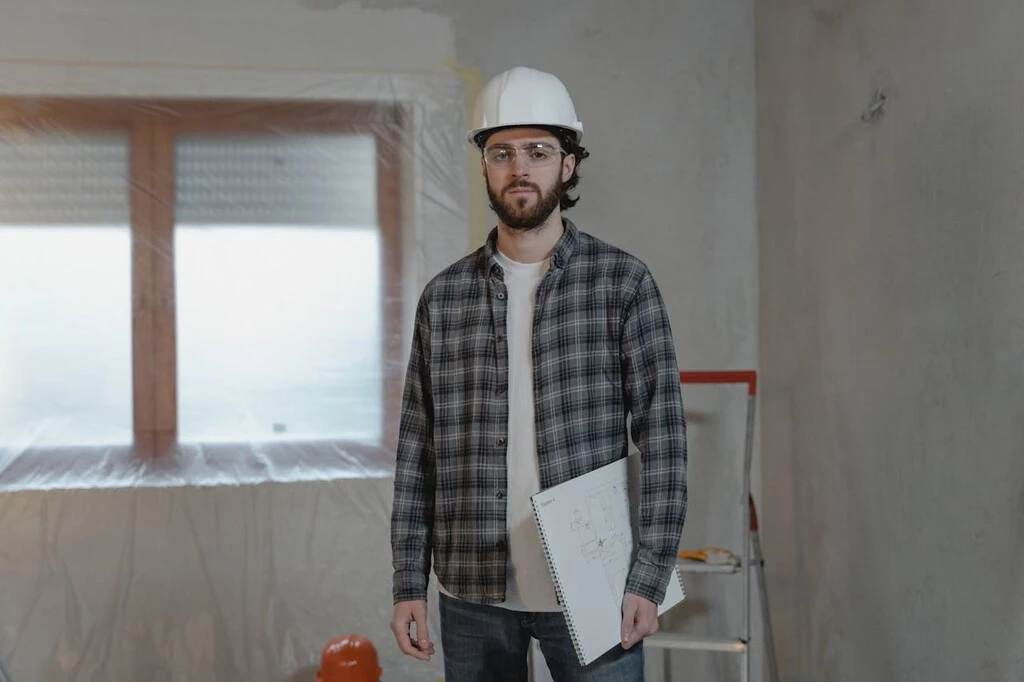 A man with a white helmet and a shirt holding a paper