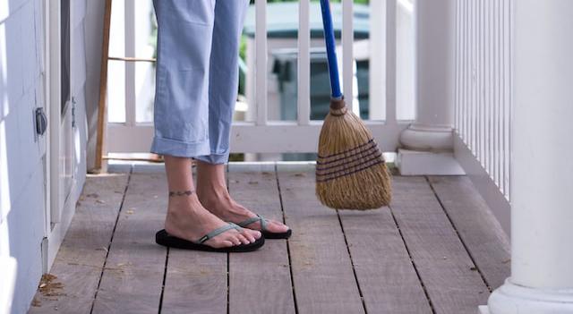 Woman using a broom on a deck.