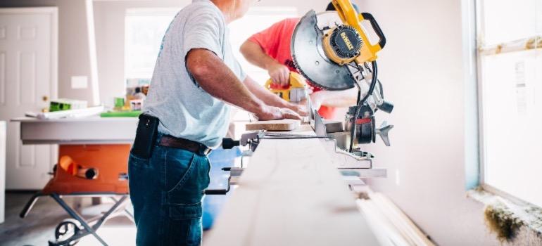 Two men using a saw to cut wood planks