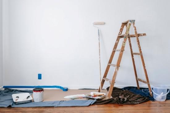A ladder and a paintbrush in a white room