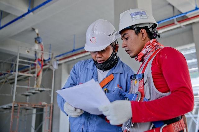 Two men with helmets discussing a construction project.