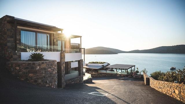 A picture containing outdoor, sky, water, shoreDescription automatically generatedA house near the ocean during the day. 