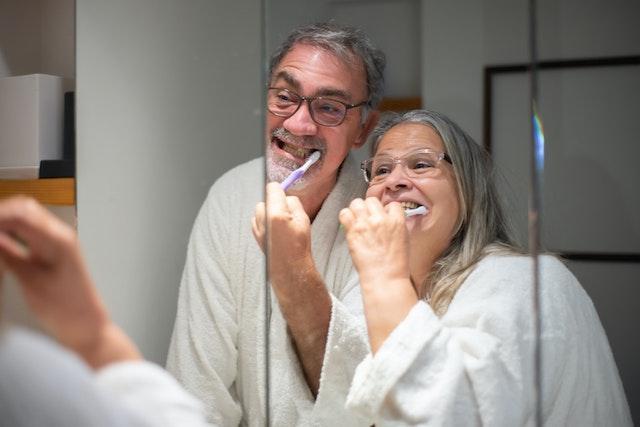 An elderly couple brushing their teeth 