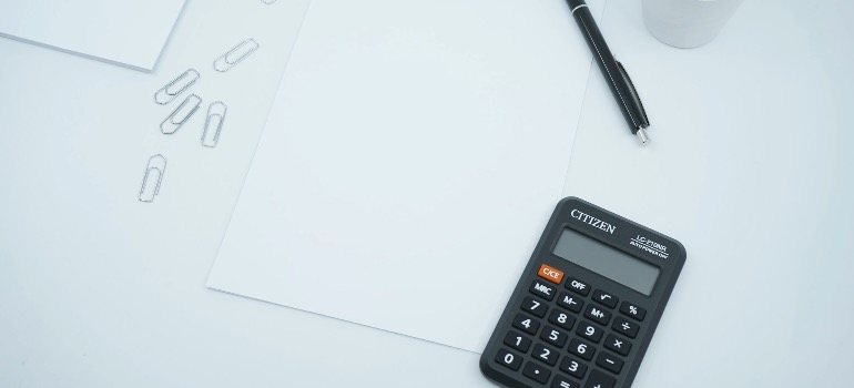 A blank paper on a desk next to a pen and calculator