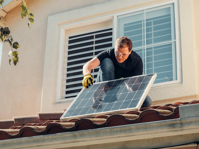 Man standing on a roof and holding a solar panel