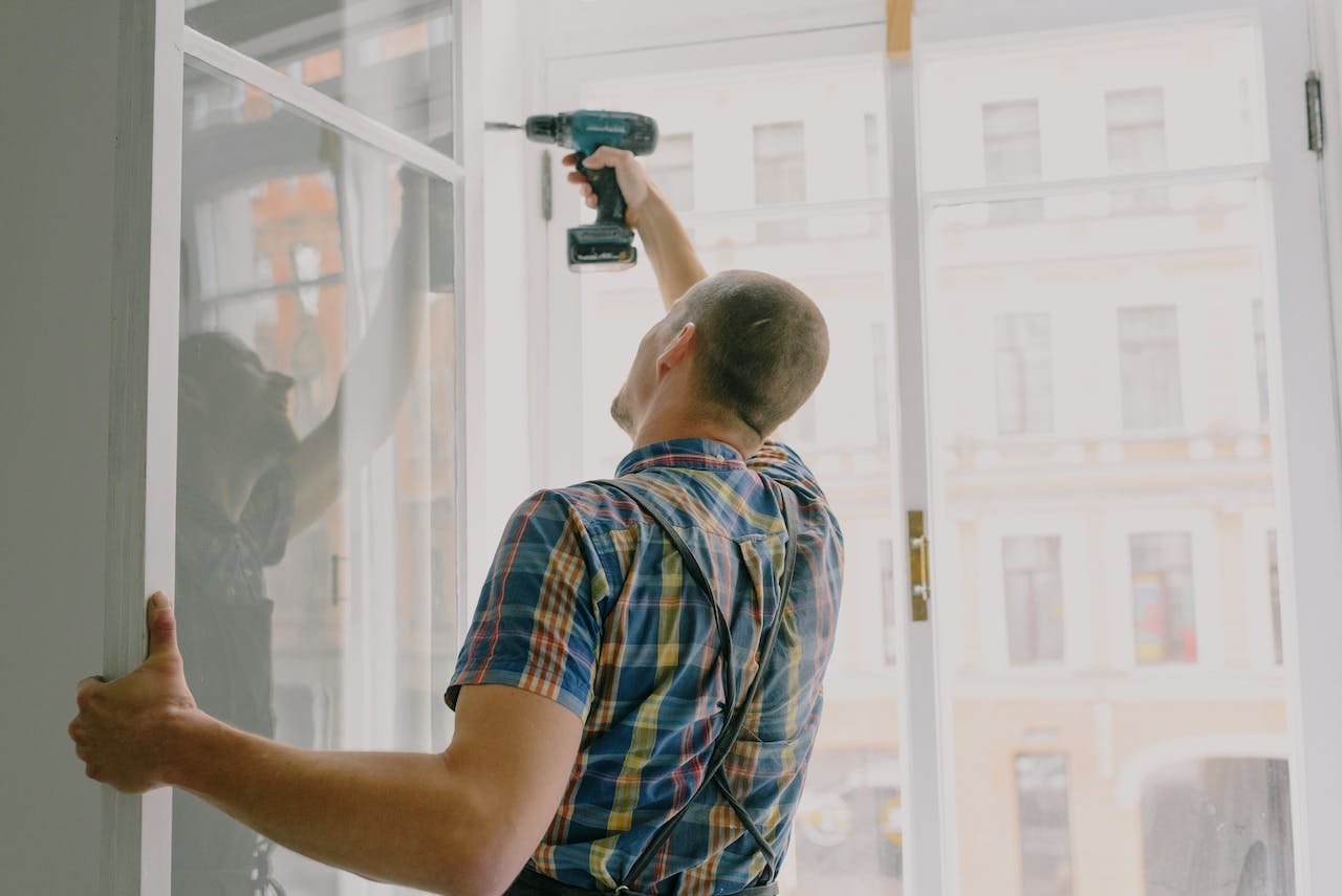 A person fixing the window with a drill.