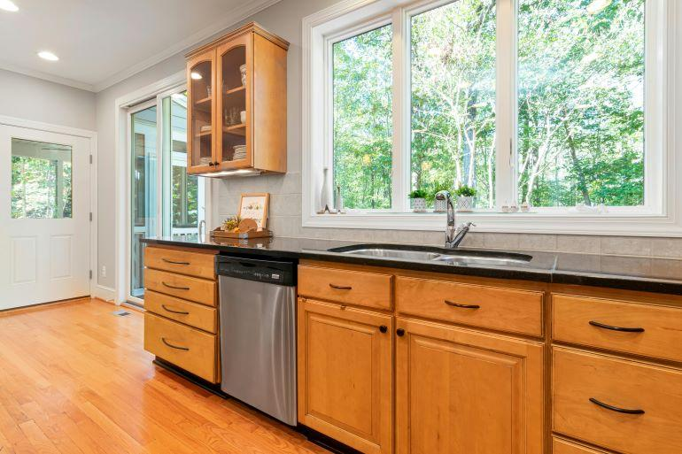 Bright kitchen with wooden cabinets, large window, and sink area showing an existing layout ready for a creative kitchen redesign.