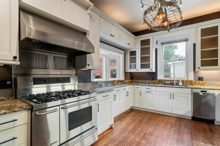 Modern renovated kitchen with white cabinets, stainless steel appliances, and upgraded lighting.