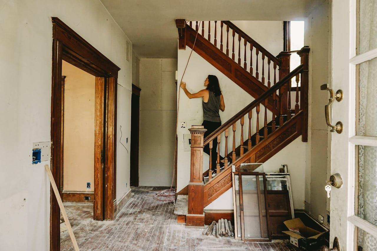 A woman in a grey tank top standing on a wooden staircase