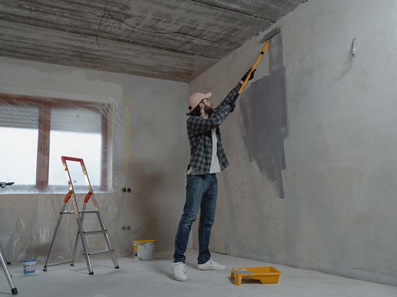 A man painting a wall to prepare an inherited house for sale.