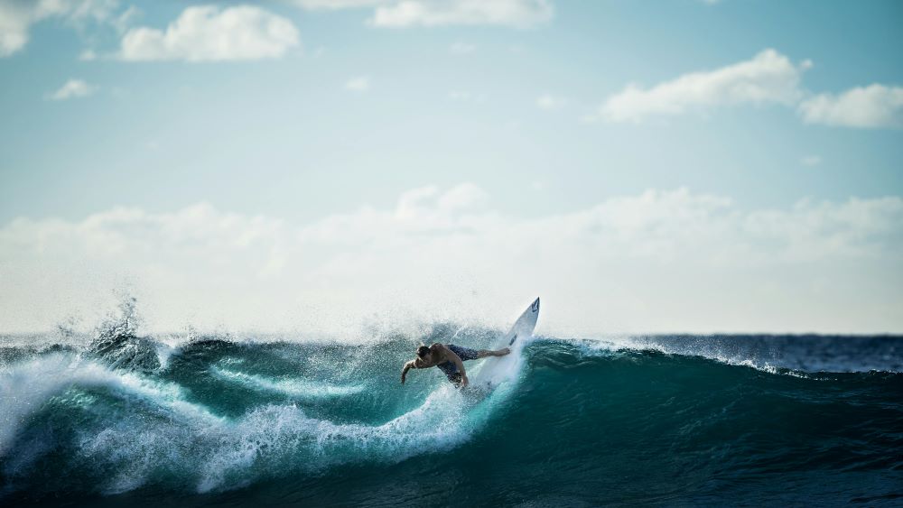 A man surfing during the day. Caption: While the sea can be a lot of fun, it can also create problems.