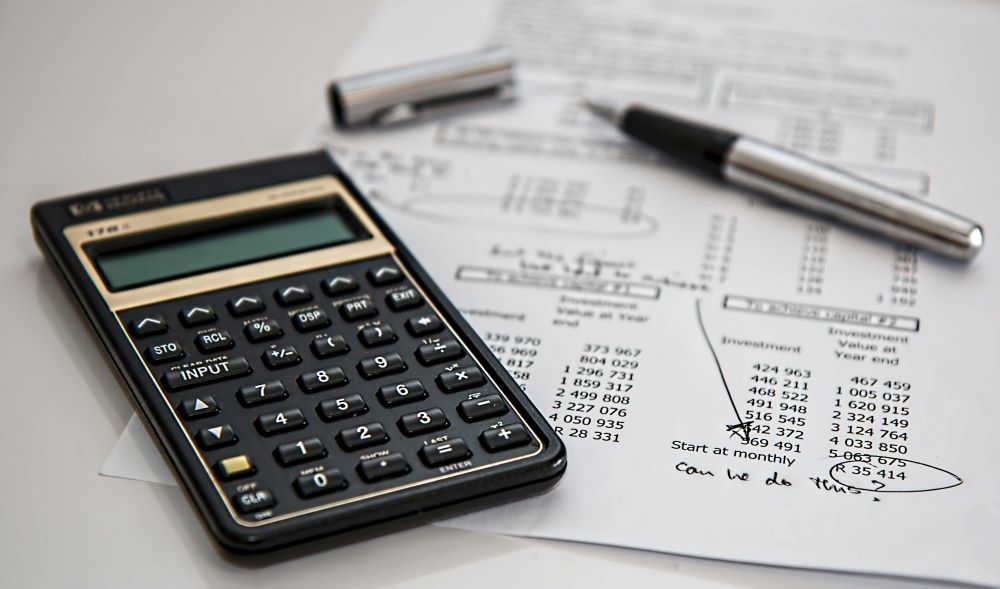 A calculator, a pen, and white paper on a table. Caption: Prioritize long-term sustainability to save money.