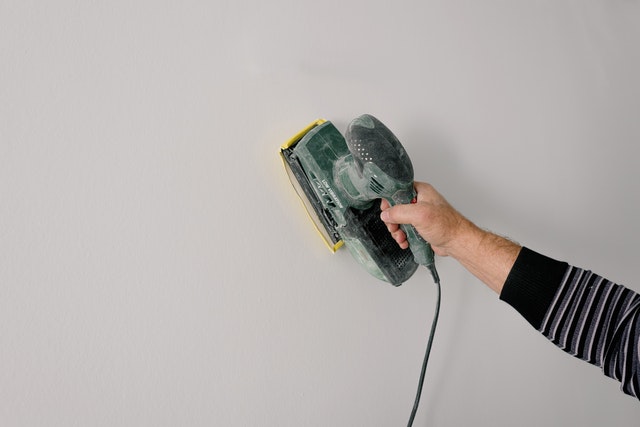 Person polishing wall with construction tool. 