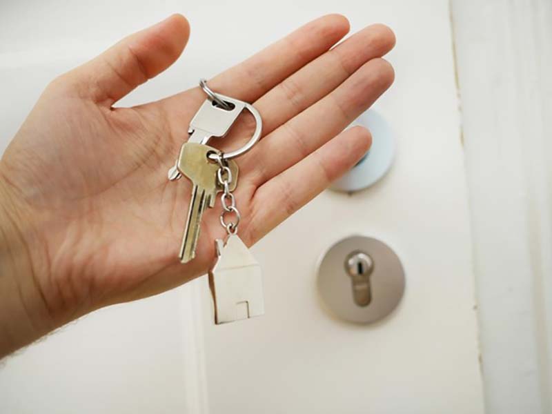 Person holding keys in front of a door