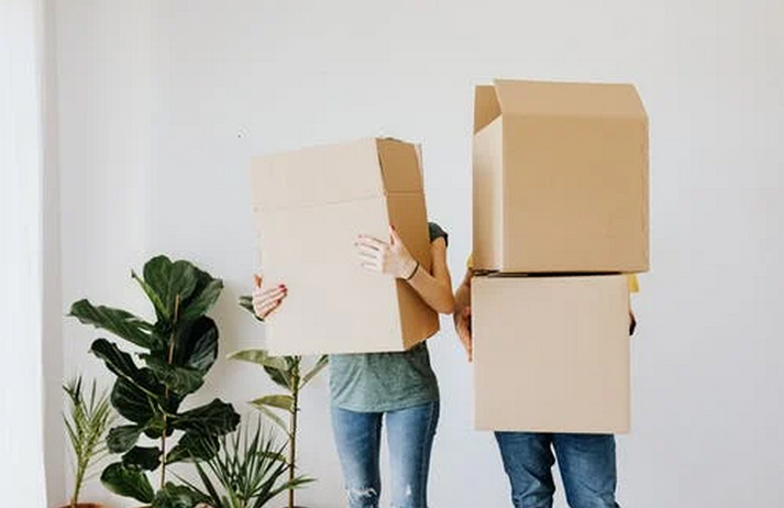 A couple carrying boxes into their new home