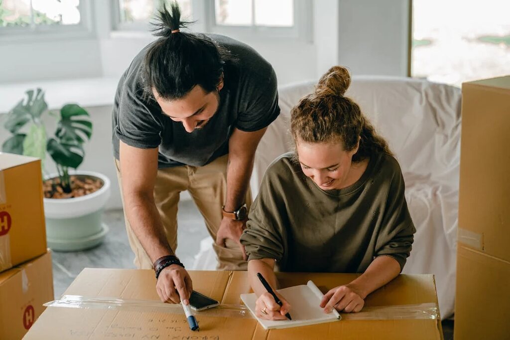 A couple writing in a notebook on a cardboard box