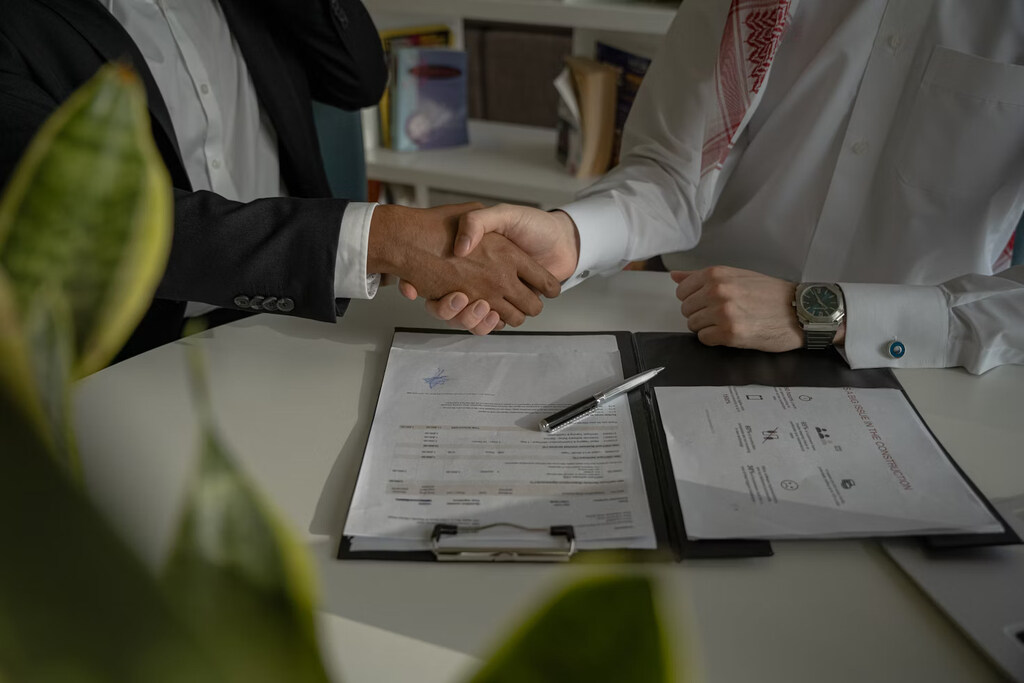 Two people shaking hands over a piece of paper