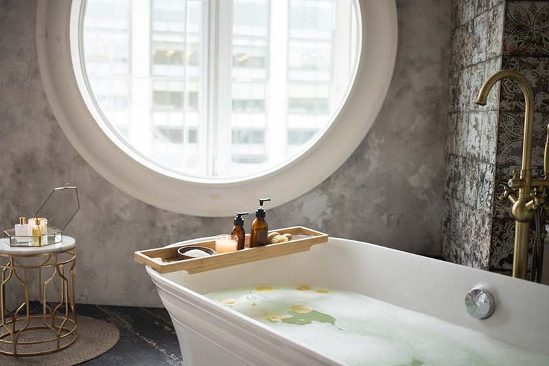 Interior of a bathroom with skin care supplies and a rounded window.