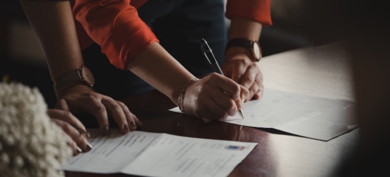 Two people signing contracts