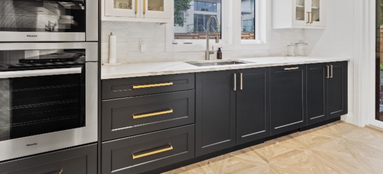 A picture of a kitchen with black and white cabinets